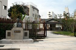 写真：公園入口の漱石像と漱石情報発信施設（右奥）