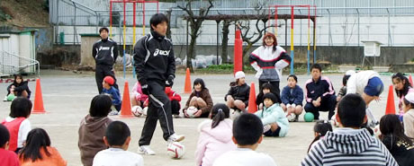写真：校庭で相馬さんの話を聞く子どもたち
