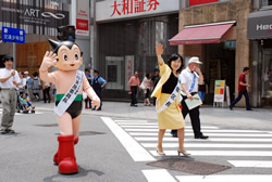 写真：手を振る中山区長と一日実施委員長の鉄腕アトム