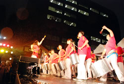 写真：雨の中太鼓を叩く「エスコーラ・ジャフロ」のメンバー