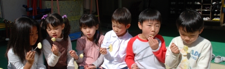 写真：園庭でリンゴを食べる園児たち