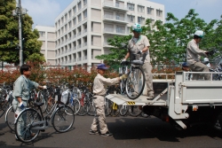 写真：女子高校生が乗りやすい大きさに整備した自転車をトラックに載せる