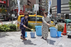 写真:浴衣を着て打ち水を行う地域の方