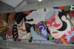 写真：完成した壁画から、くまどりをした歌舞伎役者の顔がガードの上下いっぱいに描かれている