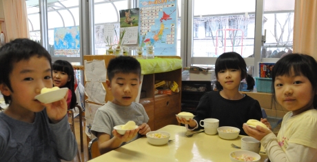 写真:切り分けられたリンゴの乗った子皿を掲げる子どもたち