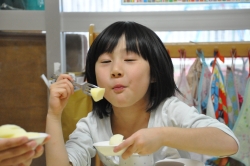 写真:リンゴをおいしそうにほおばる子ども