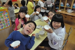 写真：リンゴを食べ終わり空になった小皿を掲げる子どもたち