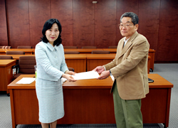 写真:宇都木座長代行から報告書を受け取る中山区長