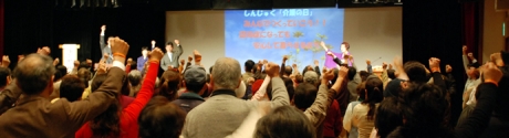 写真:参加者全員でオレンジリングをした腕を高く上げる