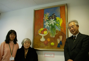 写真:絵画「よみがえる」の前で久栖さん(中央)と施設関係者
