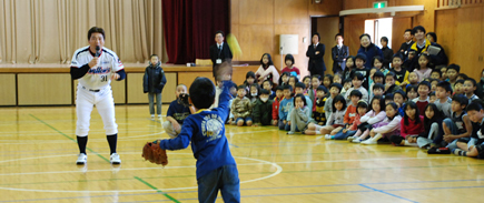 写真：キャッチボールをする真中さんを子どもたちが見つめる