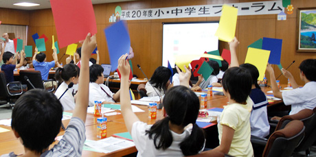 写真:色紙を高く掲げて自分の意見を表現する子どもたち