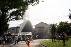 写真:防災部の放水で水浴びする子どもたち