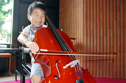 写真:笑顔でチェロを弾く男の子