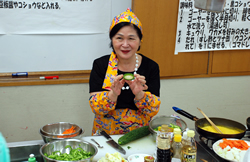 写真:ゴーヤを手に説明する高山さん