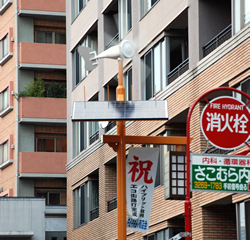 写真:風を受けて回る日中のハイブリッド街路灯