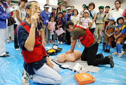 写真:AEDの使用方法を聞く参加者