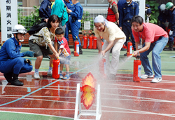 写真:訓練用消火器で火(的)を消す参加者
