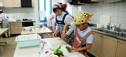 写真:包丁を握る男の子と見守るお母さん