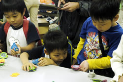 写真:昔の遊び・今の遊びコーナーでこま遊びをする子どもたち