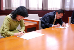 写真:協議書にサインする中山区長と桑原議長