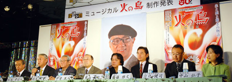 写真:記者会見壇上の8名。背景には手塚治虫氏の写真とミュージカル火の鳥ポスター