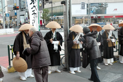 写真：新宿三丁目交差点での托鉢・募金をする人々