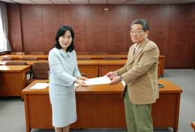 協働支援会議委員から区長へ報告書を提出する様子<左から新宿区長、宇都木座長代行>