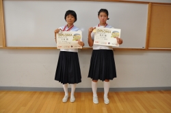 写真：全日本中学校陸上大会の表彰状を持つ長沼さん（右）と卜部さん