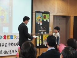 写真:防災児童画展で表彰する吉住区長