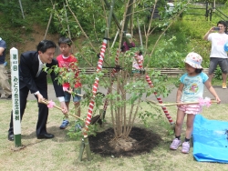 写真:記念植樹する吉住区長と子どもたち