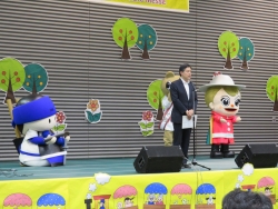写真:あいさつする吉住区長、新宿のキャラクター達と