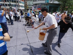 写真：吉住区長による打ち水