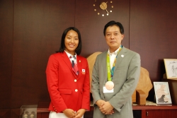 写真：三井選手と三井さんの銅メダルをかける吉住区長
