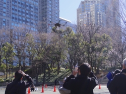 写真：高層ビル街に向けて飛び立つドローン