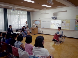 写真：車椅子をお使いの方から話を聞く児童たち