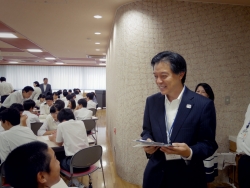 写真:班討議中の生徒と話をする吉住区長