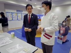 写真:子ども薬局の説明を聞く吉住区長