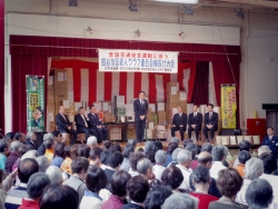 写真:たくさんの景品の前で挨拶