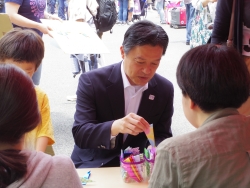写真：催しブースで折り紙を折る吉住区長
