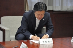 写真:吉住区長が覚書に記名する様子