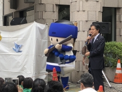 写真:明るい会のマスコット「同心くん」と一緒に挨拶