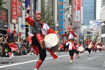 新宿エイサー祭りで伝統衣装を着て太鼓を叩きながらエイサーを踊る男性の写真