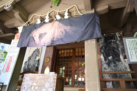 神社社殿写真(中央に「千年前の川を渡る馬」の絵の幕)