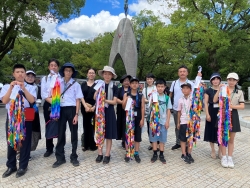 広島へ派遣された小・中学生と保護者が千羽鶴を持って撮影した集合写真